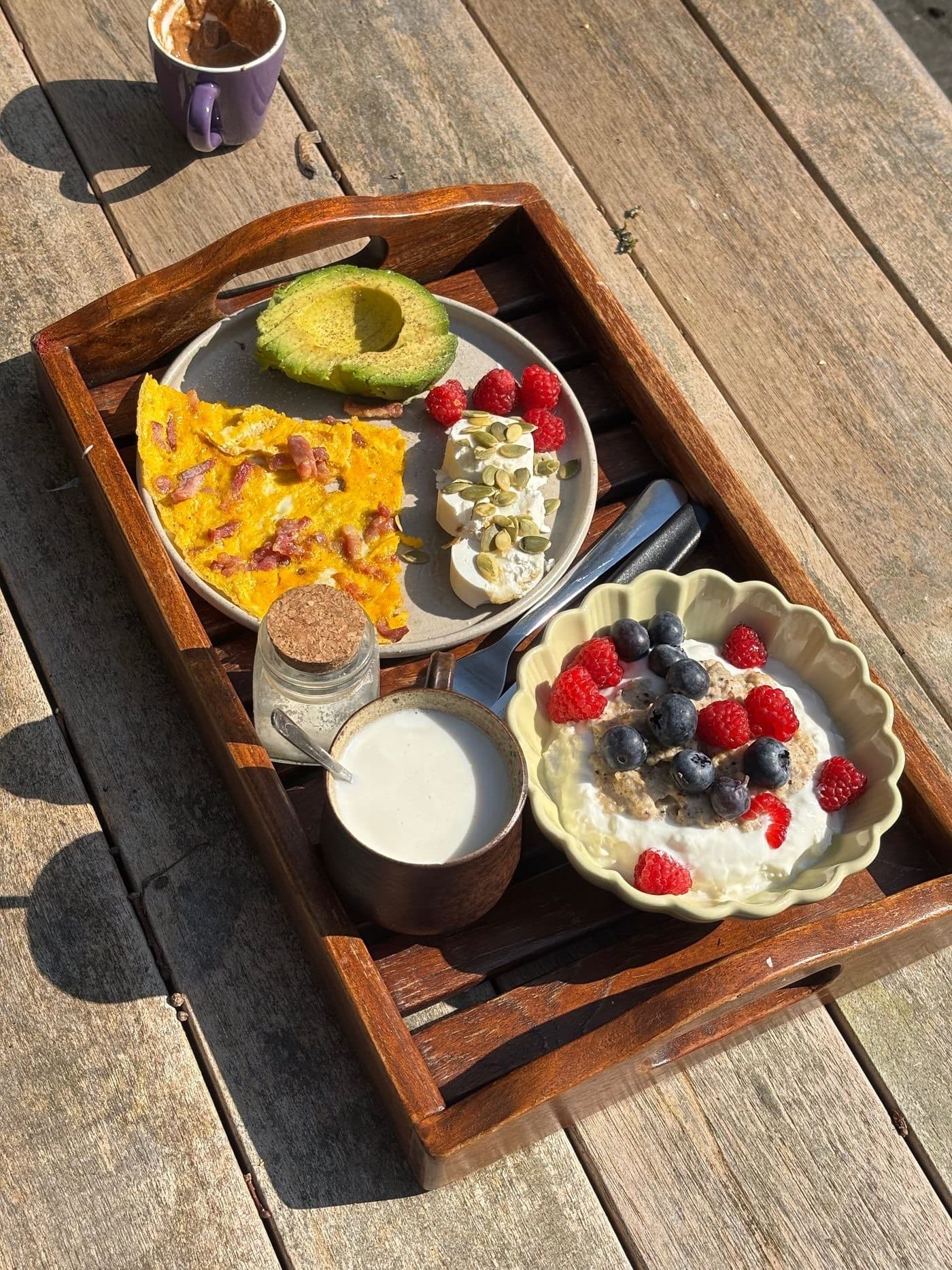 Uitgebreid ontbijt met Millit pap, omelet en avocado op een houten tafel