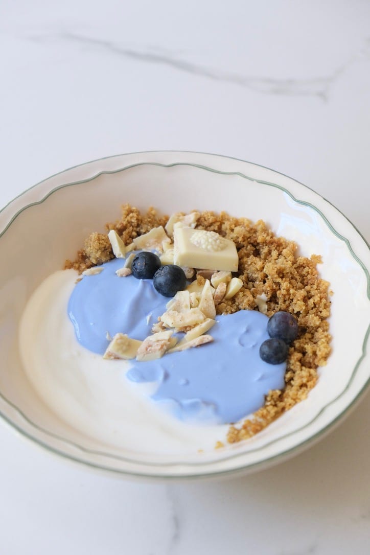 Ontbijtbowl met blauwe spirulina crème, Millit crumble, blauwe bessen en witte chocolade