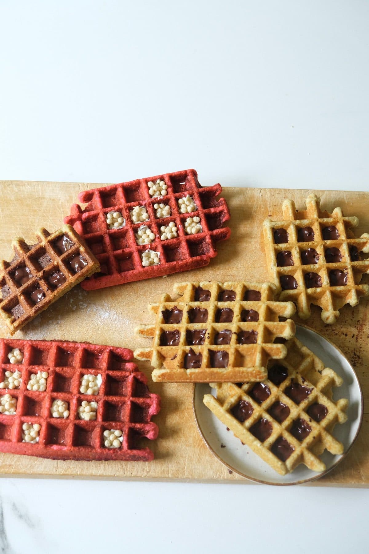 Roze en goudbruine Millit wafels met chocolade op een houten plank